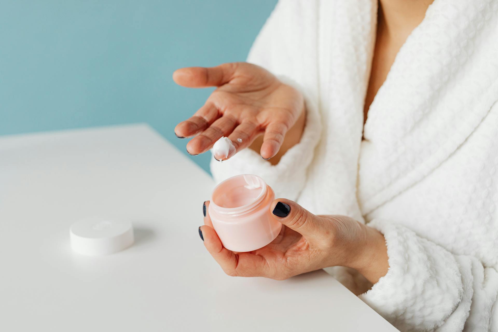 woman holding a facial cream with some on her finger